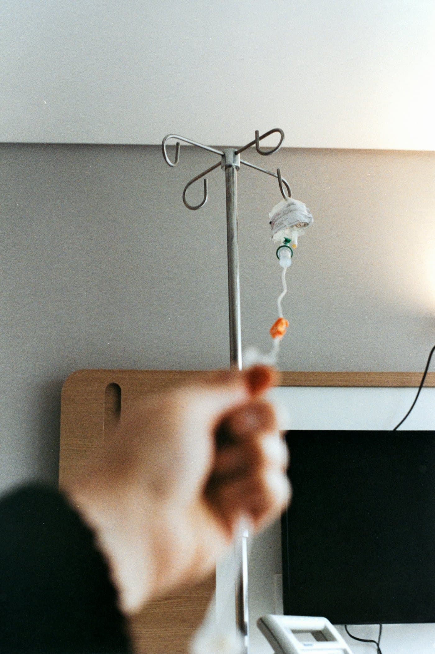 A hand adjusting an IV stand